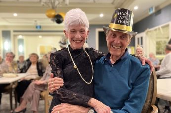 Older couple on new year's eve, woman with short grey hair sitting on lap of distinguished older man